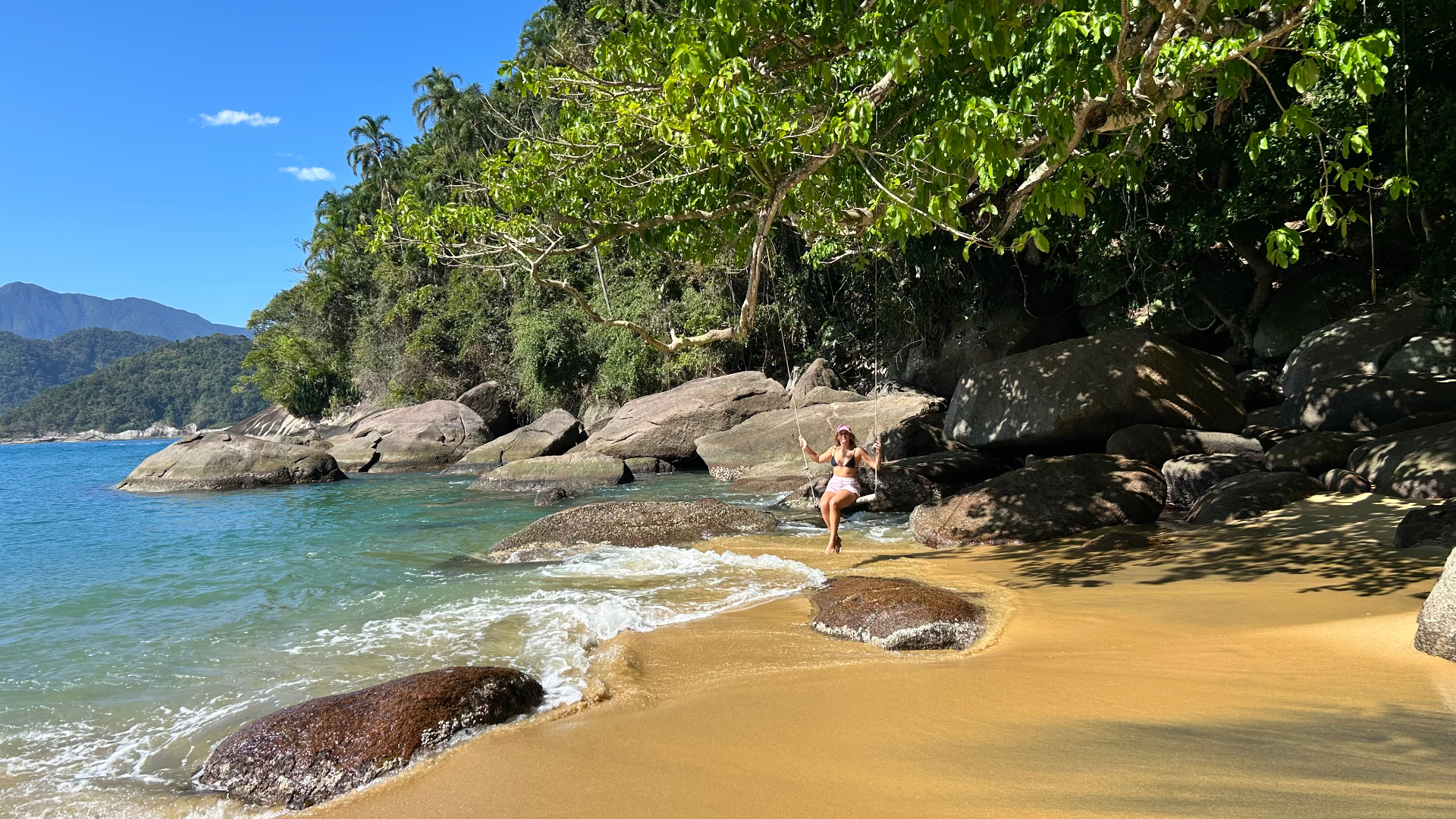 Balanço de corda em praia de areia dourada com água turquesa